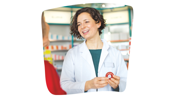 Una farmacéutica vestida con una bata blanca sujeta un rollo de esparadrapo Leukoplast mientras aconseja a una clienta en su farmacia. Una farmacéutica vestida con una bata blanca sujeta un rollo de esparadrapo Leukoplast mientras aconseja a una clienta en su farmacia.